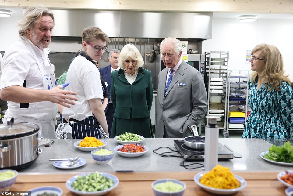 Queen Camilla, 76, opted for a stylish emerald green skirt suit with black knee-high boots and black leather gloves, and antique pearl drop earrings for the public outing - with both royals needing umbrellas to brave the inclement Oxfordshire weather. The Coronation Food Project was inspired and devised by the King, who has long been concerned about waste, particularly when it comes to food, and the cost of living crisis. More than 12million tons of food is wasted each year in the UK alone. The project will work with, and crucially raise funds for, existing food waste projects around the country to save and circulate more surplus food and use it for social good. It will help scale up nationwide projects and build warehouses, as well buy fridges, freezer and refrigerated lorries. The project is being led by Baroness Casey and Dame Martina Milburn and co-ordinated by the King Charles III Charitable Fund.