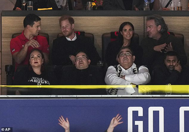 Prince Harry speaks to an official in his seat