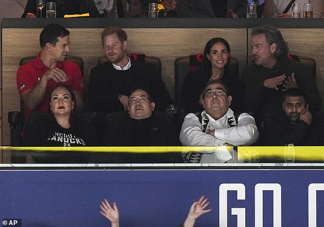 Prince Harry speaks to an official in his seat