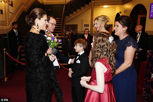 The eldest child of King Carl XVI Gustaf , 46, opted for a sophisticated monochrome ensemble, which featured light feathered fabric. Pictured being presented with flowers