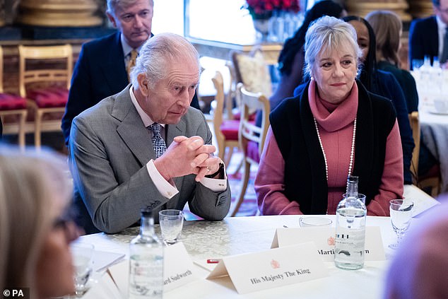 King Charles, 75, engaged in conversation with a number of individuals seated at a round table