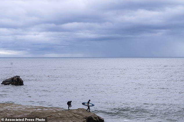 A surfer jumps in the water near Steamer Lane as storm clouds approach in Santa Cruz, California on Wednesday, Dec. 20, 2023