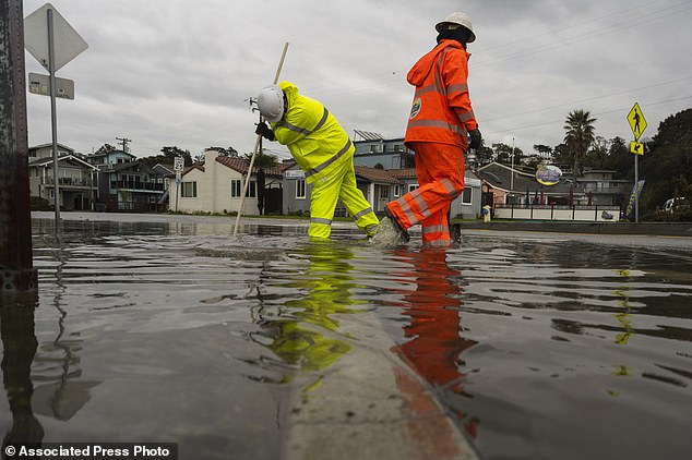 Santa Cruz County public works employees clear a storm drain in the Rio Del Mar neighborhood of Aptos, California on Wednesday, Dec. 20, 2023