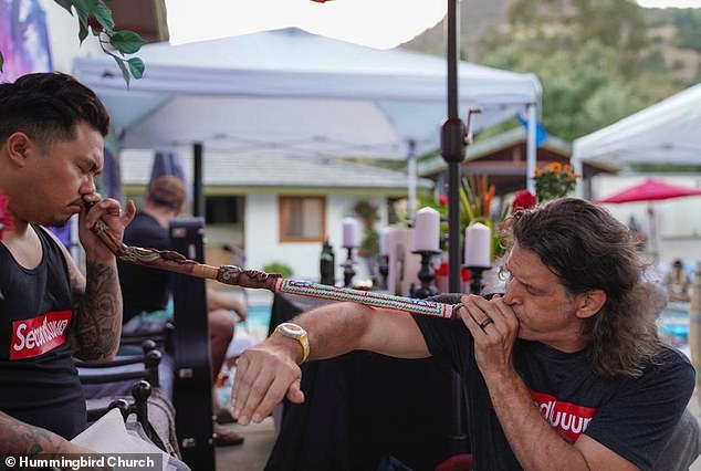 A Hummingbird Church member blows 'rapeh', a tobacco snuff, up another's nose using a pipe called a 'tepi' to prepare them for an Ayahuasca ceremony in Temecula, California