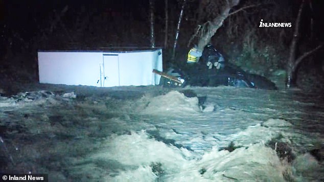 Mudslides, flooding and gale-force winds are battering much of California as a severe storm system continues to deluge the west coast for a second day. (Pictured: first responders rescue three people who became trapped in a vehicle amid flooding in San Bernardino County)