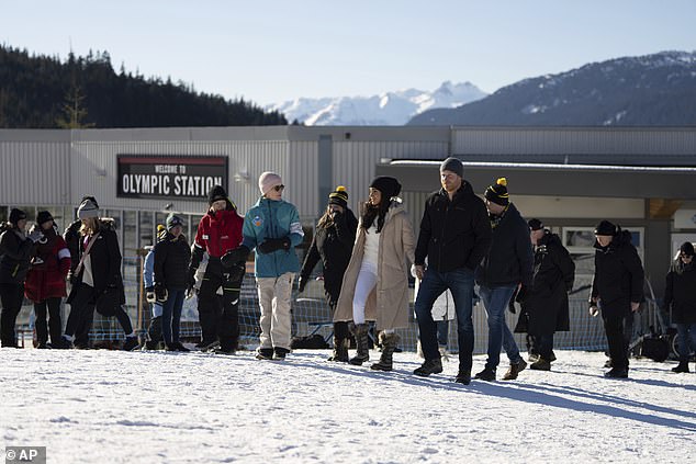 Prince Harry and Meghan talk with one of the ski-resort staff during their visit