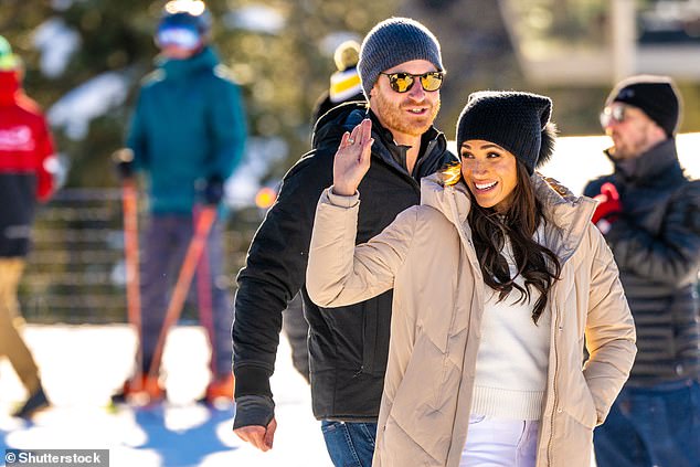 Meghan waves at the crowd as she walks onto the mountain with Harry