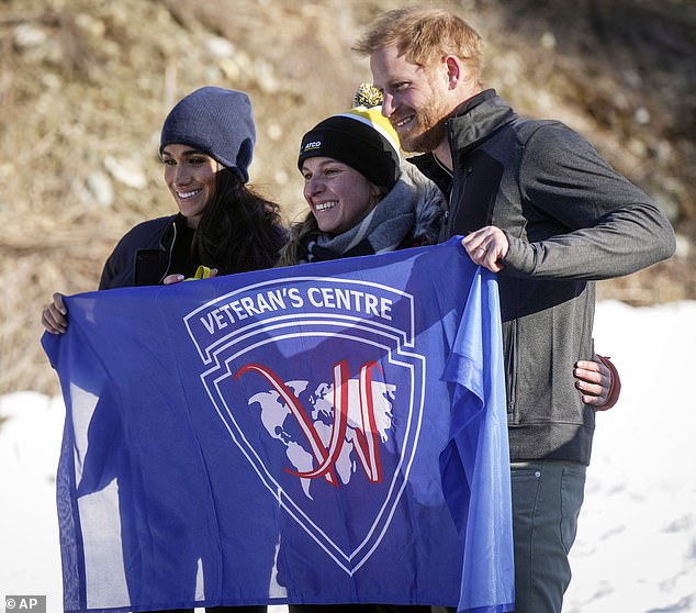 Meghan and Harry pose with a woman holding a flag during their trip to Whistler