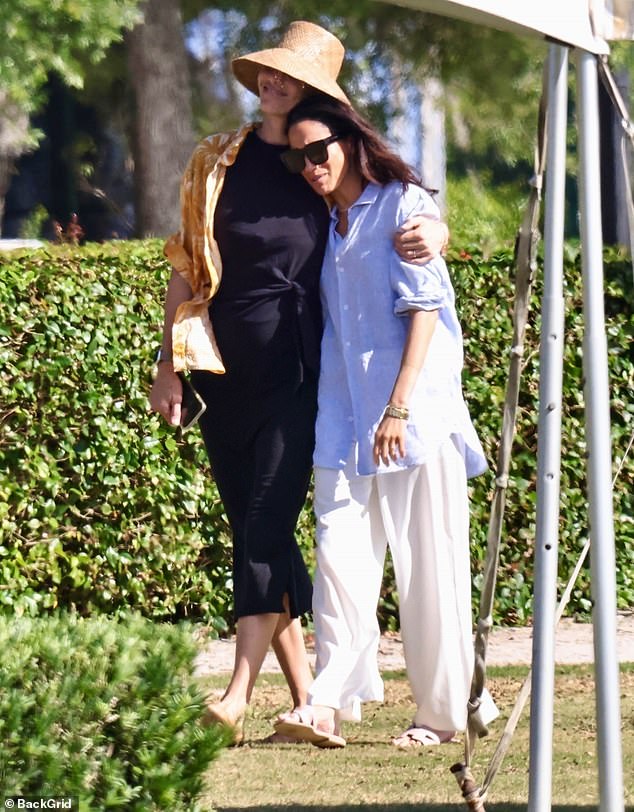 Meghan Markle, seen here with a hat-covered woman believed to be Delfina Blaquier, traded her stilettos for $760 Hermes flip-flops and breezy linens one day after being mocked for her impractical on-field attire at a charity polo match in Miami, Florida