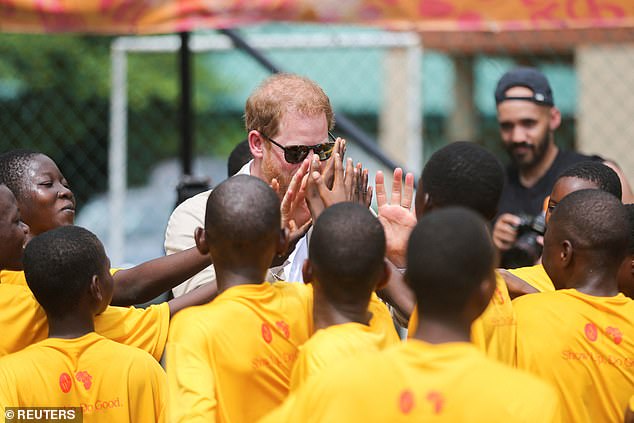 Harry gives high-fives to children at a local school as he attends a basketball event in Lagos