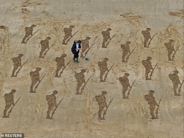 The MoD confirmed last night that there would now be 'four UK A400M aircraft involved'. A drone view shows a member of Royal British Legion Industries (RBLI) clearing away sand on sculptures of some 80 soldiers as part of an installation erected on Stone Bay, ahead of the 80th anniversary of the D-Day landings, in Broadstair