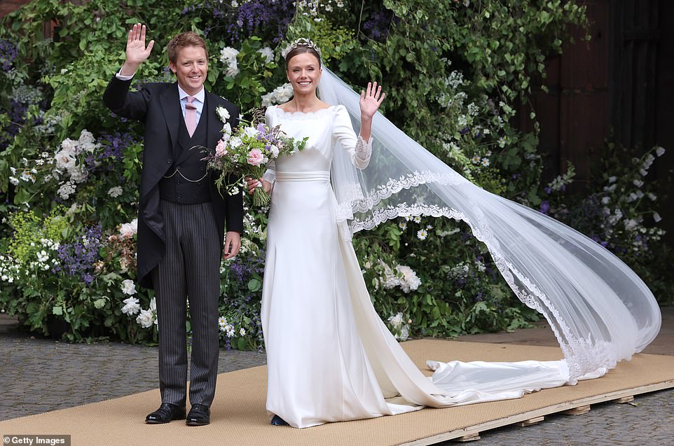 Hugh and Olivia smile and wave at the crowds after their wedding at Chester Cathedral