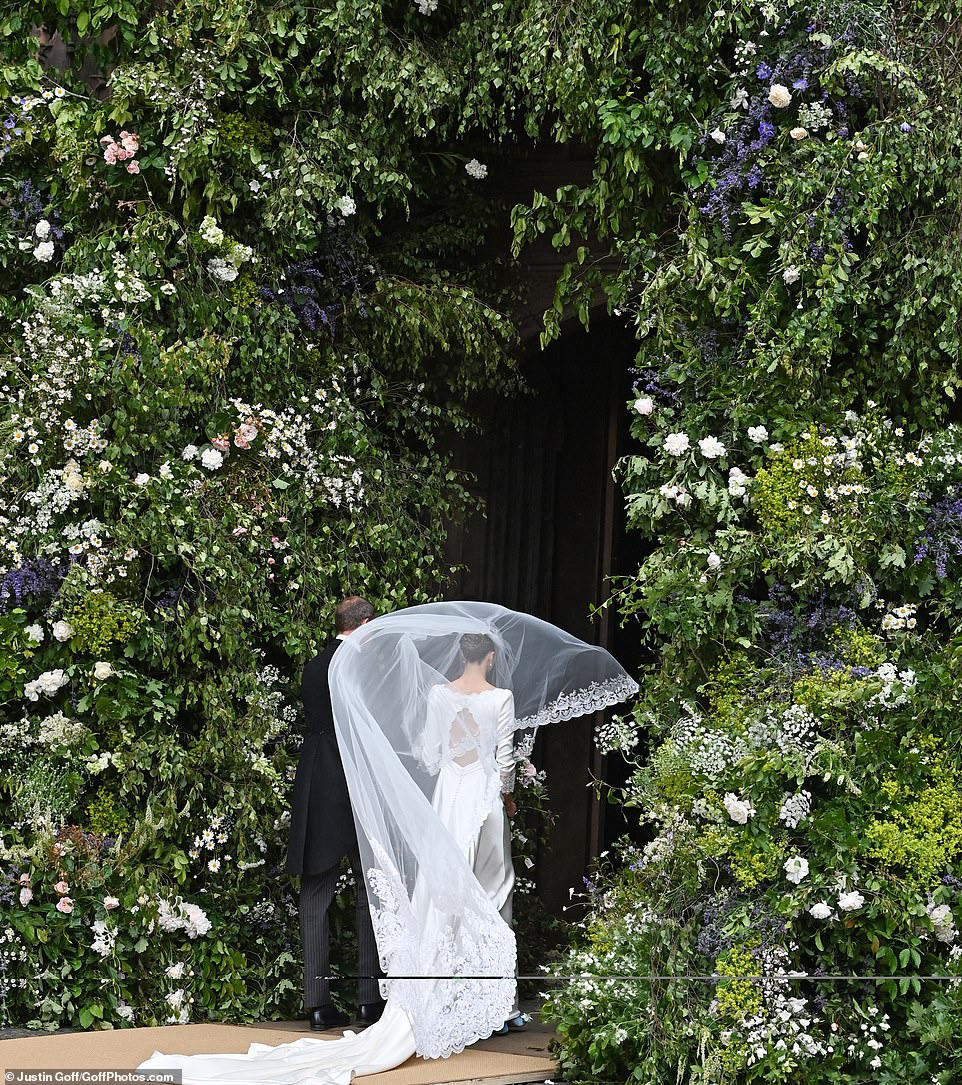 Olivia walking through the stunning flower arch displayed on the entrance to the Cathedral