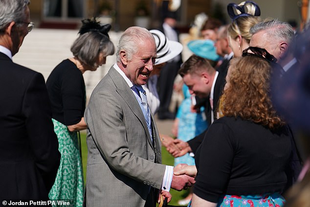 King Charles III speaks to guests attending the garden party at Buckingham Palace