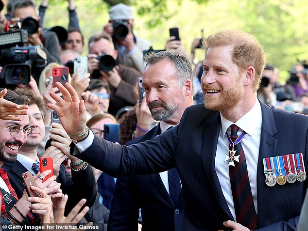 Prine Harry waves and peaks to members of the public as he leaves the service at St Paul's Cathedral on May 8