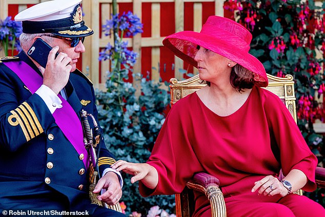 Prince Laurent is scolded by his wife as he speaks on the phone during National Day celebrations in 2022