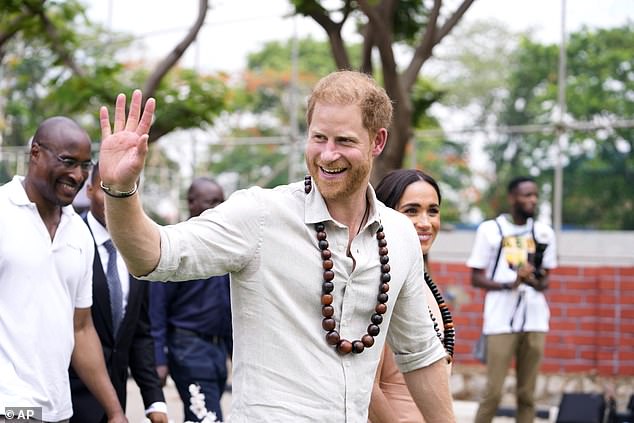 Prince Harry waves as he meets children at the Lightway Academy in Abuja, Nigeria, on Friday