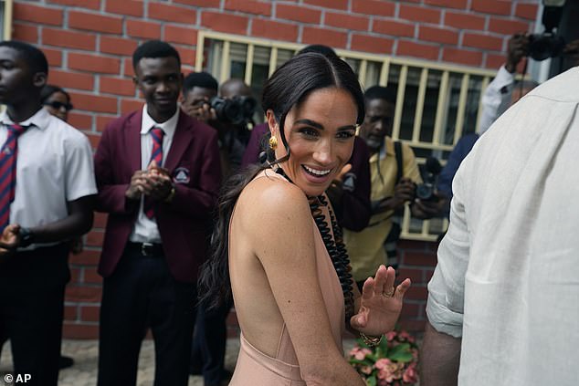 Meghan waves as she and Harry meet children at the Lightway Academy in Abuja on Friday