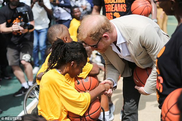 Harry shakes hands with a young basketball player as he joined the children at their practice