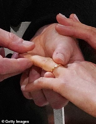 Prince Harry places the wedding ring on the finger of Meghan Markle during their wedding service at St George's Chapel