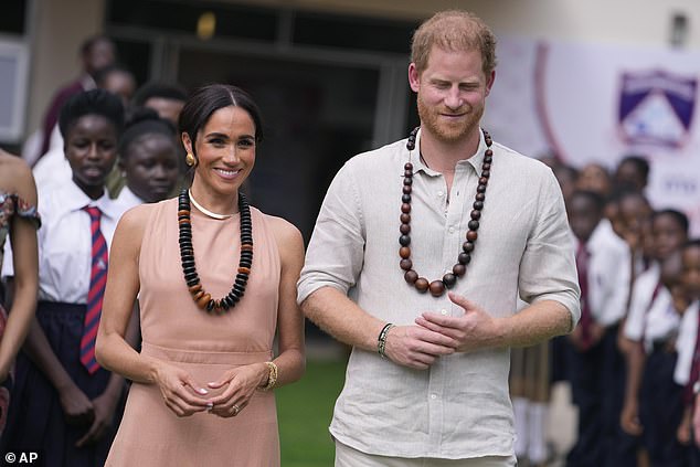 Harry and Meghan pictured smiling as they begin their tour of Nigeria with a trip to the Wuse Lightway Academy today