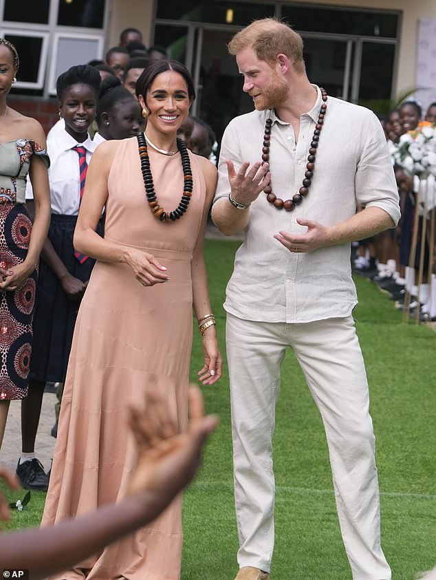 Harry and Meghan chat as they meet children at the Wuse Lightway Academy in Abuja today