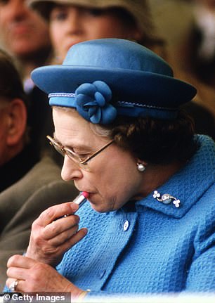 Queen Elizabeth II puts on lipstick in the Royal Box at the Windsor Horse Show on May 11, 1985