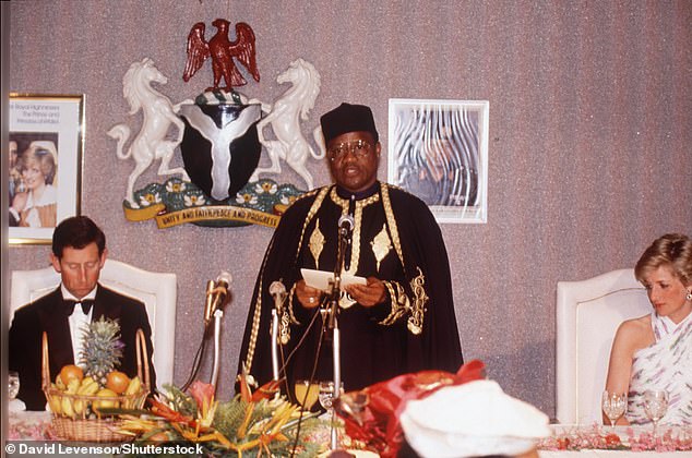 Prince Charles and Diana look distinctly awkward as they sit two seats apart at a banquet during their Nigeria tour