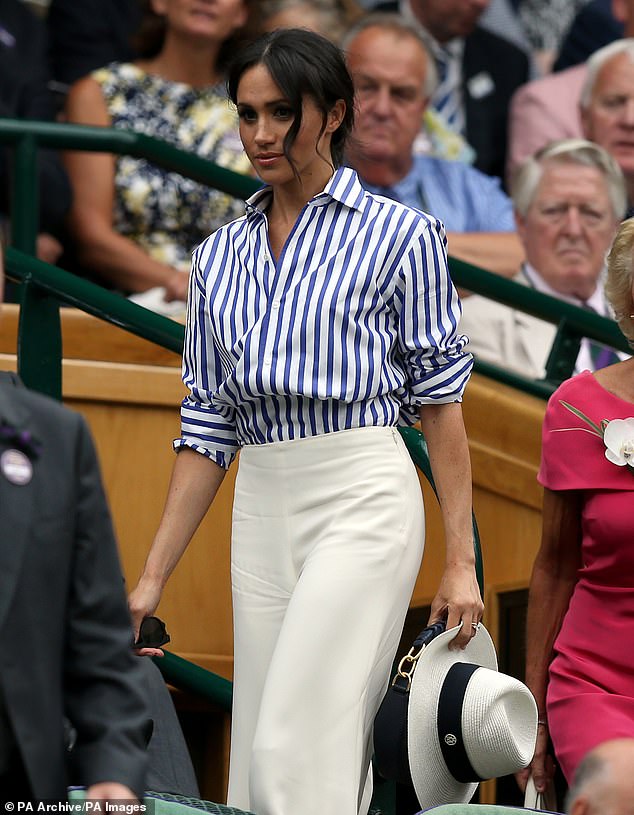 While Kate wore a white dress featuring a tennis ball design, Meghan (pictured) opted for wide-leg trousers with a blue striped shirt