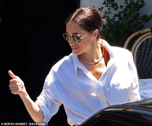 Meghan, who is snapped while giving Kimberly a thumbs up, has been spotted wearing her £15,500 Cartier necklace on previous occasions