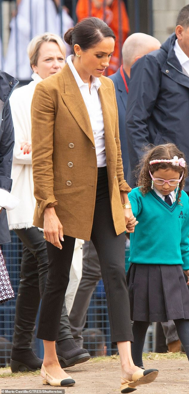 Meghan looked sophisticated in black high-waisted cigarettes pants, which paired with a white button-up business shirt with one button at the top left undone, tucked in. Jacket, Loro Piana, £2,800; Princess Diana's butterfly earrings; slingbacks, Chanel, £910; Cartier watch and Cartier love bangle, as before