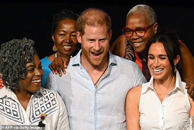 Harry smiles during a group photo after Meghan's talk on Afro women in power