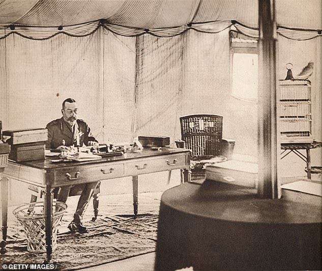 King George V with his pet parrot named Charlotte inside the work tent at Buckingham Palace gardens in 1936