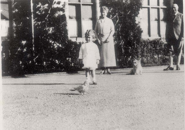 Princess Elizabeth seen in 1928 at Balmoral standing next to Charlotte the parrot, the bird owned by her grandfather King George V. Behind her is Queen Mary, her grandmother