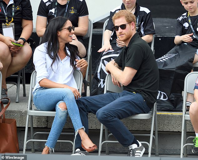 Meghan laughs as she turns towards her boyfriend as they watch proceedings in Toronto