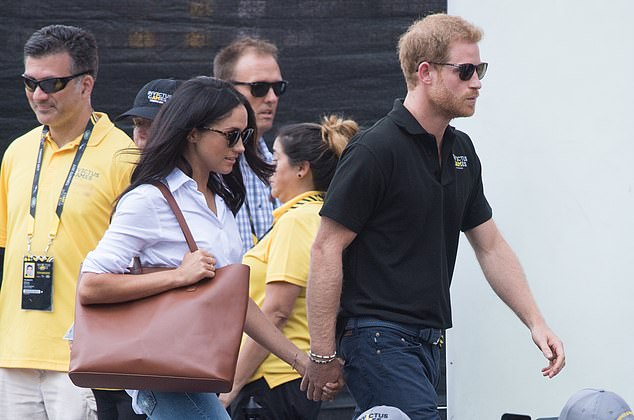 The couple holding hands as they walk to their seats to watch wheelchair tennis