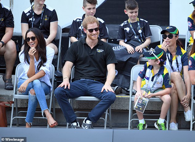 Meghan and Harry smile as they interact with nearby children during the game