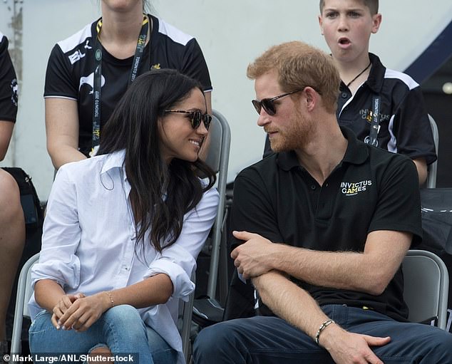 Meghan leaning in as Harry speaks during the event in Toronto in 2017