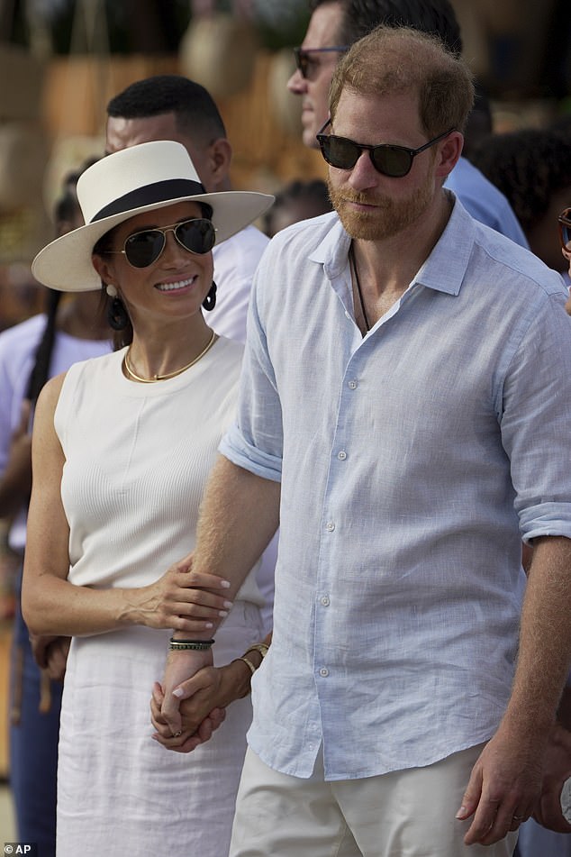 The Duchess holding Harry's arm and hand in Colombia last month