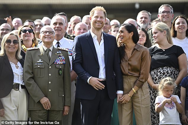 Meghan holds Harry's hand in hers as they meet with NATO Joint Force Command and families from Italy and Netherlands during day five of the Invictus Games in Dusseldorf, Germany, September 2023