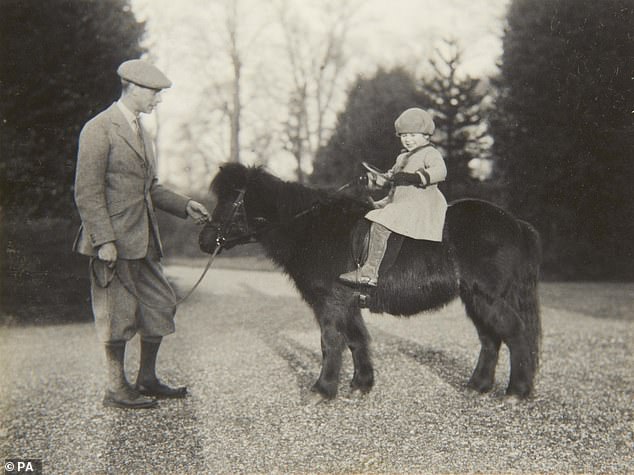 Queen Elizabeth, age four, riding on Peggy the Shetland Pony while her father, George VI, holds the leash in 1930