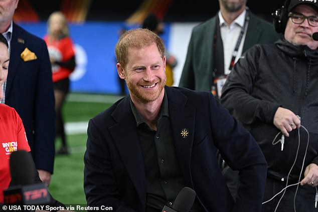 Prince Harry beams as he gives an interview to The Sports Network before being escorted away swiftly