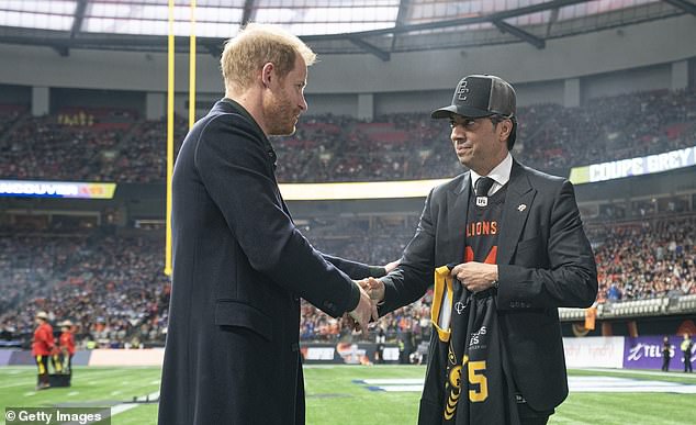 Prince Harry shakes the hand of Amar Doman, owner of the BC Lions, after presenting him with an Inivictus Games jersey