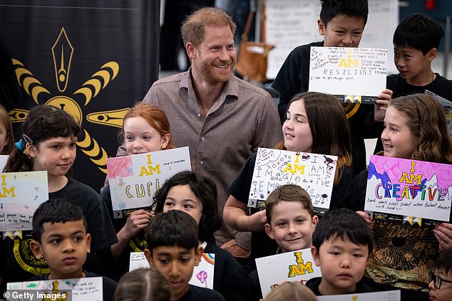 Prince Harry reading placards and signs made by students during the event