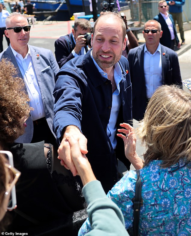 Prince William, Prince of Wales is greeted by well-wishers during a visit to Kalk Bay Harbour