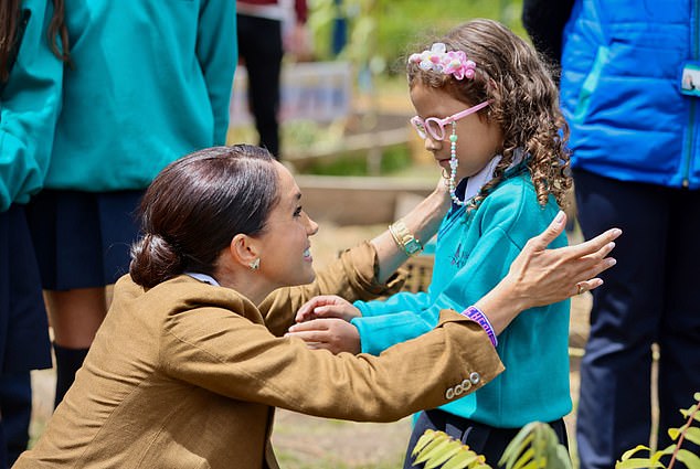 Meghan smiled as she spoke to a little girl in the school's garden, where she and Harry helped them plant trees