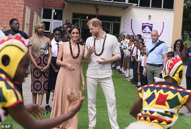 Harry and Meghan chatted to each other as they met children at the Wuse Lightway Academy in Abuja