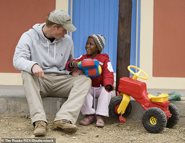 Prince Harry playing with a child in Lesotho, Africa during his visit in 2008