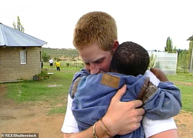 The prince hugging a young child in Lesotho during his gap year visit in 2004