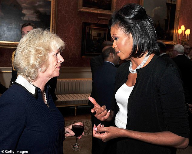 Camilla holding a glass of red wine while chatting to Michelle Obama in London in 2009